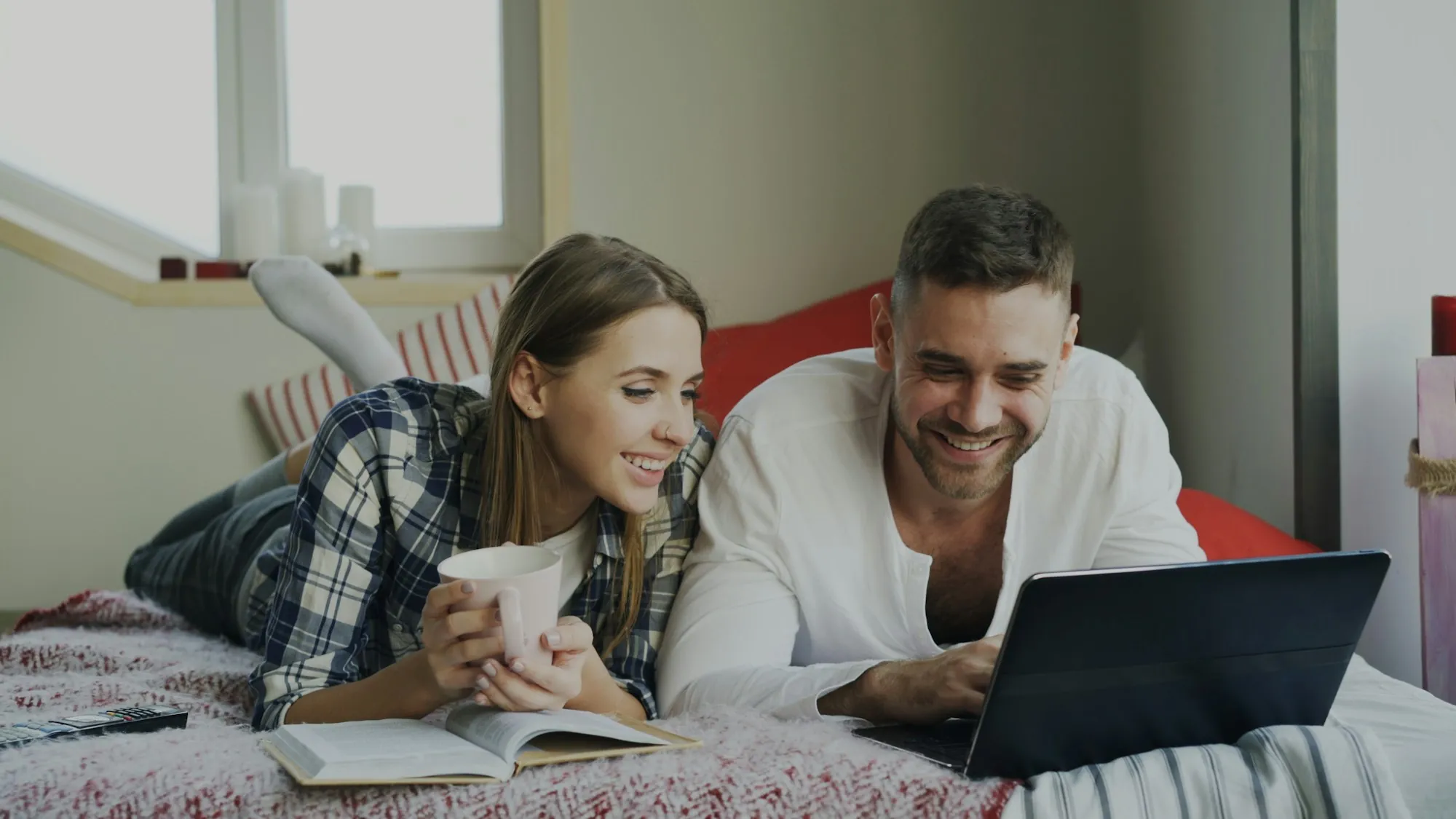 Couple lying on a bed looking at a laptop