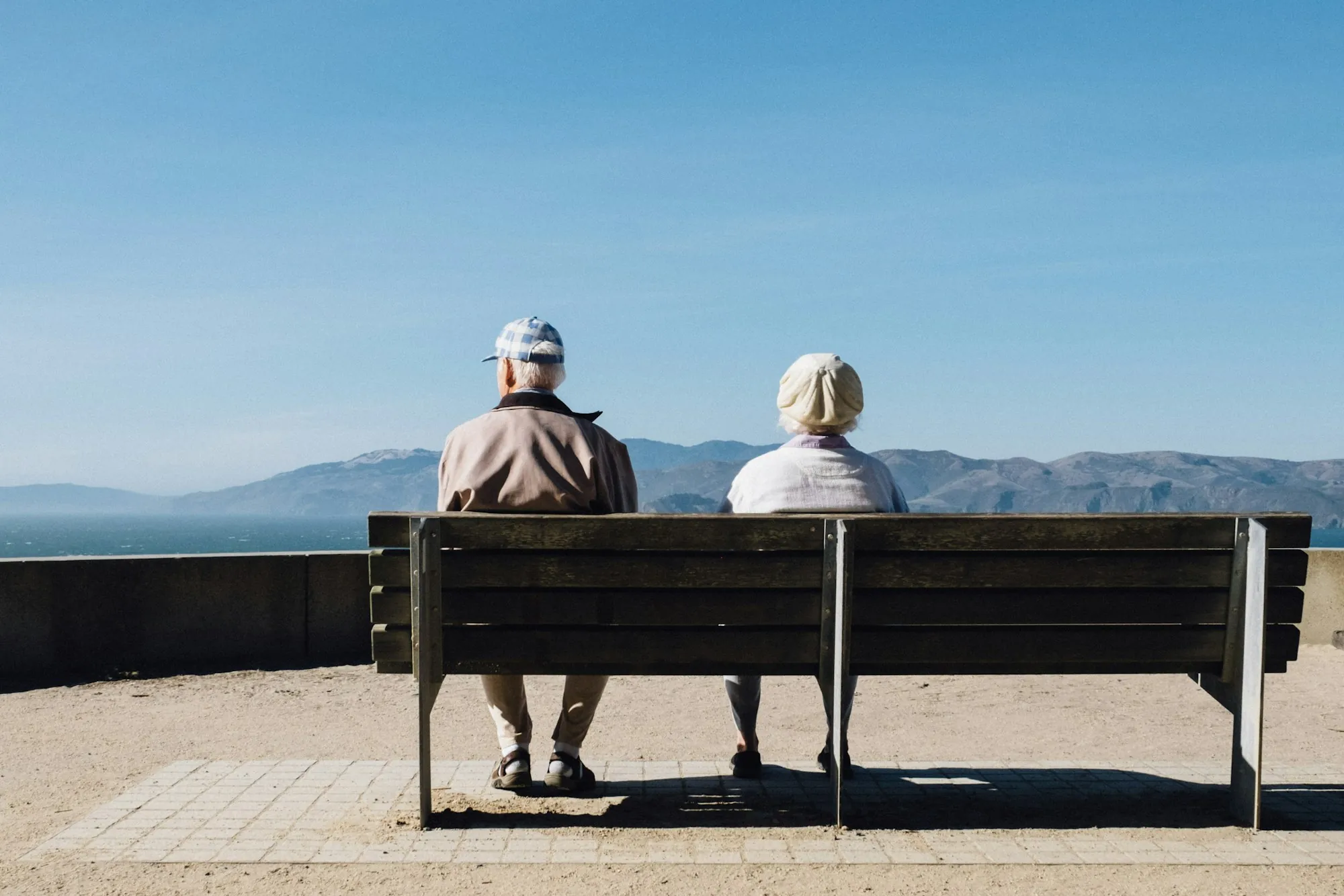 Senior couple sitting on a bench overlooking the mountains